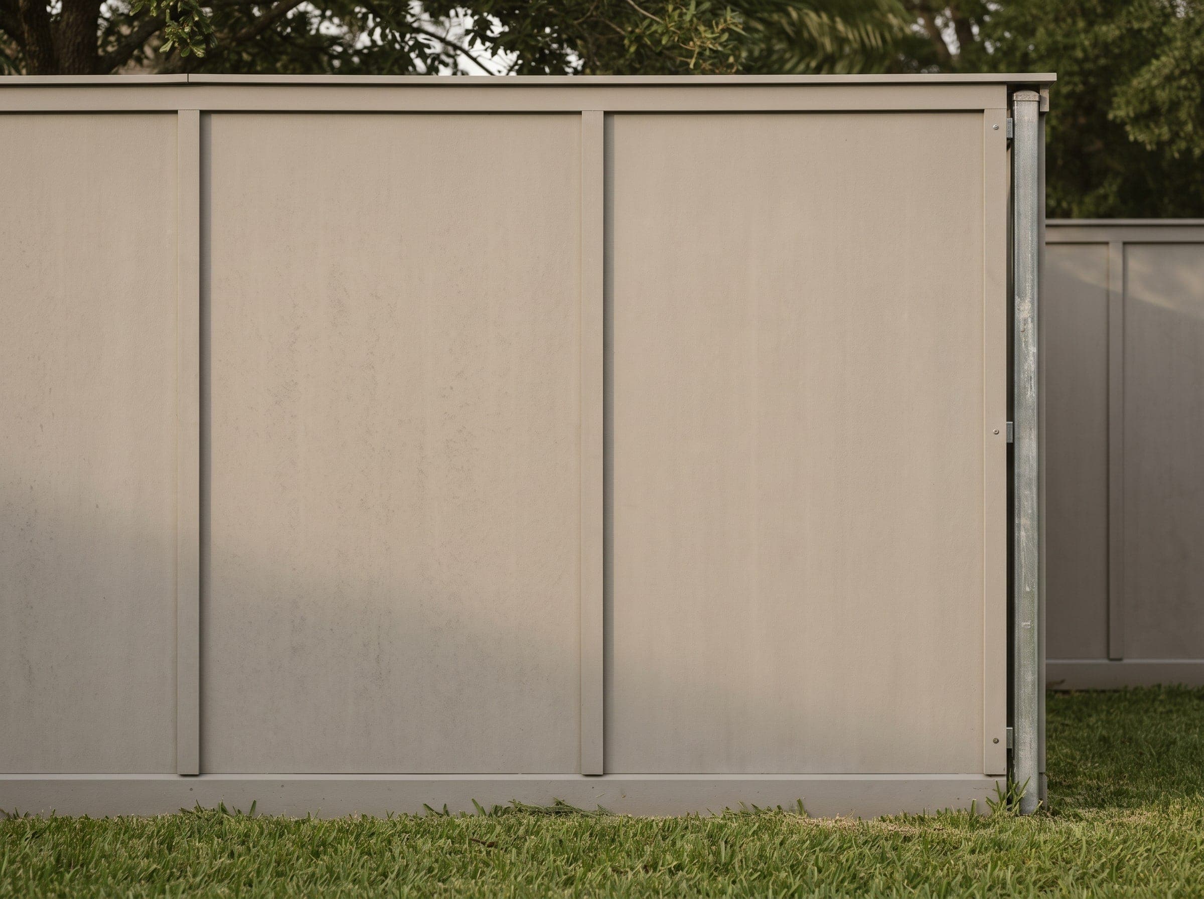 A painted fiber cement panel fence along an established Texas back yard