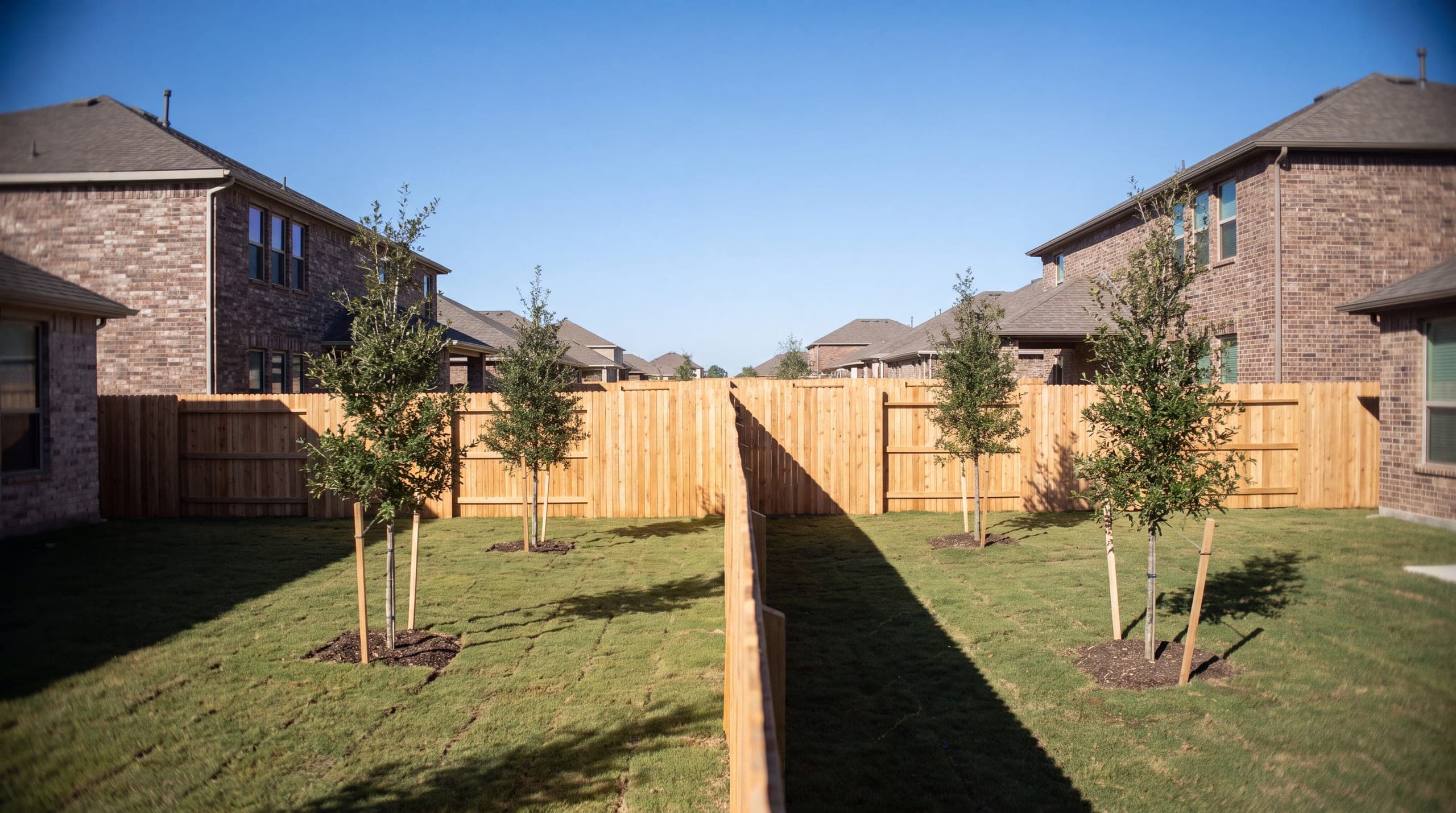 A new cedar privacy fence down the line between two new two-storey homes