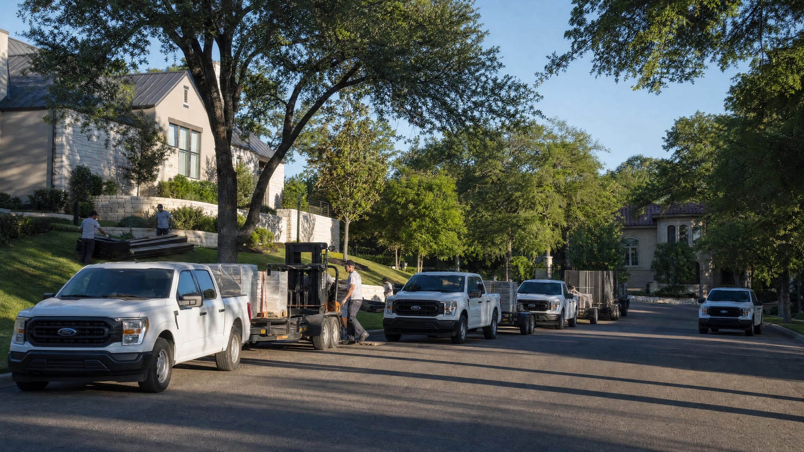 Crew trucks lined up on a subdivision street at seven in the morning