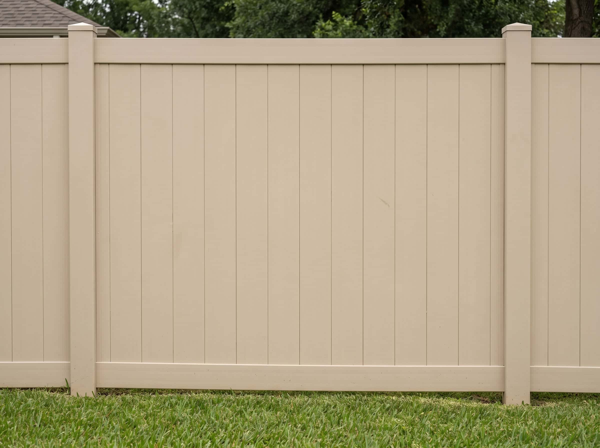 A white vinyl privacy fence around a Texas back yard